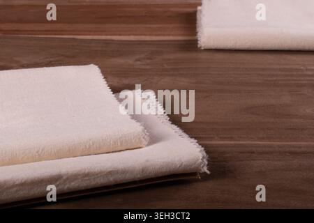 Folded natural beige matka silk fabric displayed on a wooden surface, showcasing raw silk texture and handcrafted textile elegance. Stock Photo