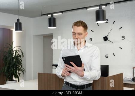 Businessman Using Digital Tablet in Modern Minimal Office Stock Photo
