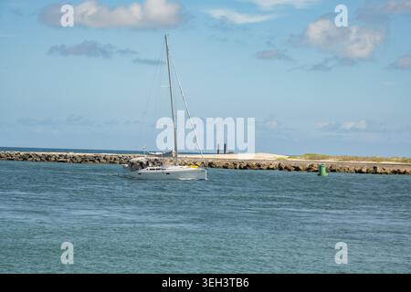 A small sailboat entering Palm Beach Florida inlet from the Atlantic Ocean in Palm Beach Shores, Florida. Stock Photo