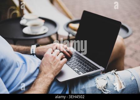 A young man works on a computer on a terrace Stock Photo