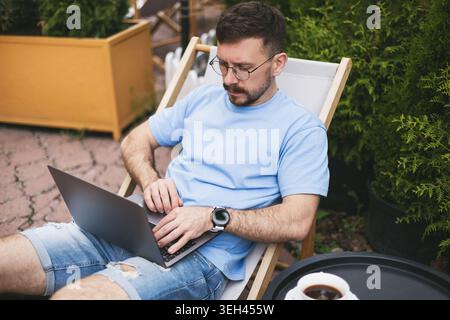 A young man works on a computer on a terrace Stock Photo