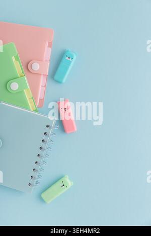 Pastel school supplies, including notebooks, binders, pens, cute highlighters, neatly arranged on a light blue background providing copy space Stock Photo