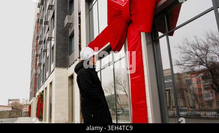 Man in a white hard hat walking near a building Stock Photo