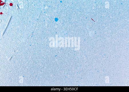 Macro close-up of a canvas painted with white, light blue and red acrylic and spray paints. Splashes, drips, stains and spray. Textured background. Stock Photo