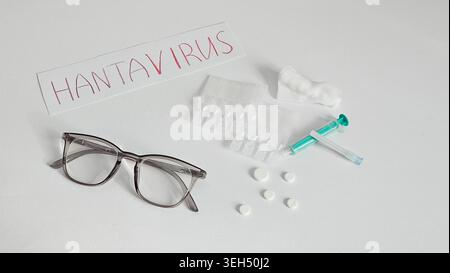 Clean healthcare flat lay with medicine pills, syringe and handwritten hantavirus label. Medical and epidemic concept with copy space. Stock Photo