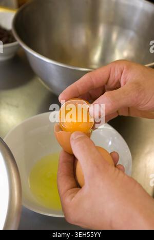 Separate the egg white from the egg yolk (film recipe: chocolate soufflé) Stock Photo