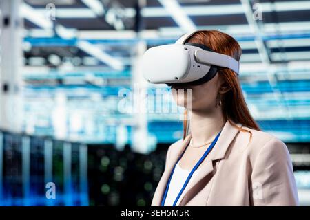 Data center programmer using VR headset gear to manage database storage mainframes. Server farm worker uses virtual reality tech to monitor internet cloud computing hardware, technology concept Stock Photo