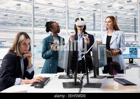 Doing microchip yield enhancement, VR headset and multiracial technicians tracking defects data. Monitoring PCB production, virtual reality and diverse coworkers in factory office Stock Photo