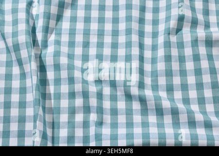 Overhead flat lay shot of a rustic, wrinkled blue and white checkered linen tablecloth. Captured under bright, sunny summer daylight with natural shad Stock Photo