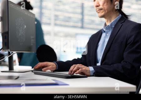Senior technician analyzing microchip architecture layouts with AI in RD office to minimize defects. Asian man examining semiconductors components with artificial intelligence to fix bottlenecks Stock Photo