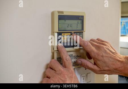 Air conditioning and HVAC engineer programming a very old split system controller. AC contractor interrogating a close control system in an office bui Stock Photo