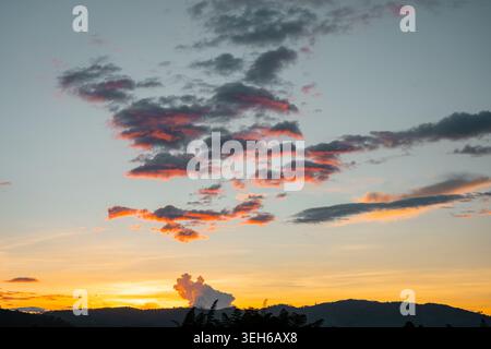 Serene sunset sky displaying brilliant orange and pink hues reflecting on scattered clouds, creating a peaceful and colorful natural landscape over di Stock Photo