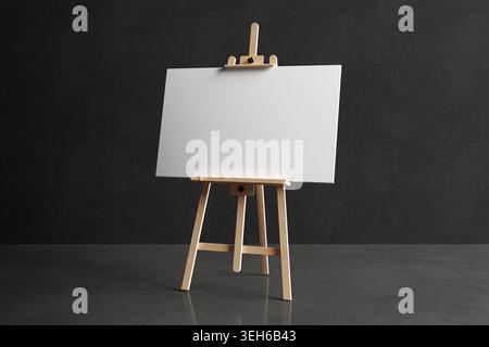 Creative Potential And Artistic Workspace Concept. Blank Canvas On Wooden Easel In Dark Concrete Studio With Empty Space For Ideas And Design. 3d Rend Stock Photo