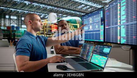 Young Aerospace Engineer Uses Laptop To Check Airplane Engine Systems. Stock Photo