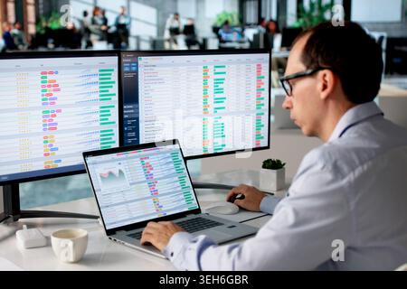 Man Reviewing Financial Bills And Medical Codes On Laptop In Office. Stock Photo