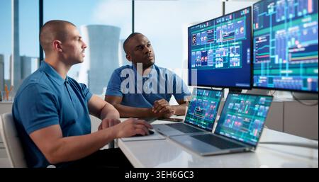 Two Engineers Use SCADA Software On Laptops To Monitor Nuclear Plant Controls. Stock Photo