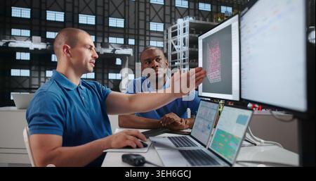 Two Engineers Using Laptops To Design Rockets In Aerospace Lab. Stock Photo