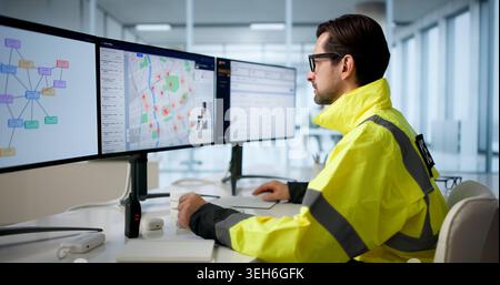 Mature Police Analyst Studies Crime Maps On Computer For Investigations. Stock Photo