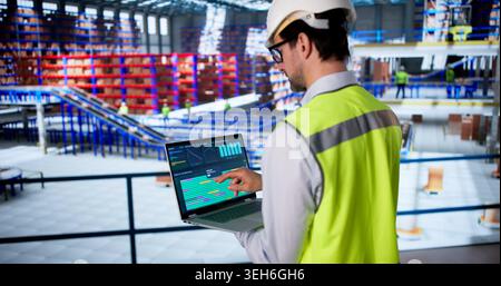 Warehouse Worker Uses Computer To Inspect Data And Monitor Safety. Stock Photo