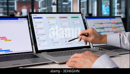 Man At Desk Using Software On Laptop To Organize Project Tasks Efficiently. Stock Photo