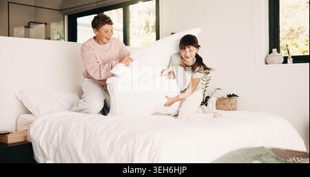 Smile, siblings and fight with pillow in bedroom for fun, playful interaction and friendly battle. Happy, children and playing with cushion, morning Stock Photo