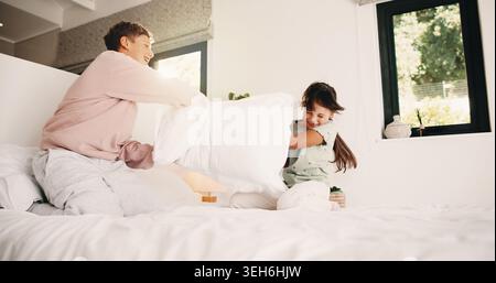 Happy, children and fight with pillow in bedroom for fun, playful interaction and friendly battle. Smile, siblings and playing with cushion, morning Stock Photo