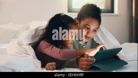 Relax, children and sisters with tablet in bed, watch cartoon or streaming video for weekend bonding. Family subscription, movie website or girls with Stock Photo