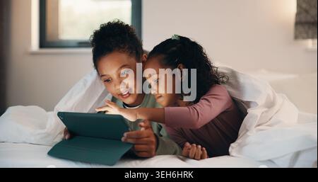 Relax, children and sisters with tablet in bedroom, watch cartoon and streaming video for bonding. Family subscription, movie website and girls with Stock Photo