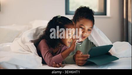 Relax, children and girls with tablet in bed, watch cartoon and streaming video for weekend bonding. Family subscription, movie website or sisters Stock Photo
