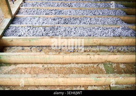 Cellulose paper insulation partially fills floor cavities of timber frame house during installation. Unfinished home construction detail, eco thermal material and energy efficiency concept Stock Photo