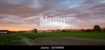Dramatic sunset over rural farmland with distant hills and stormy clouds in Mures Valley, central Transylvania, Romania. Stock Photo