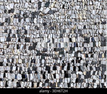 Mosaic made of black, white, gray and blue pebbles on concrete backdrop. Detail. Background and texture. Stock Photo