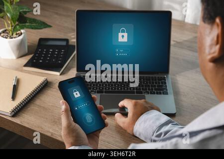 Person using smartphone with fingerprint authentication beside laptop displaying secure login interface, suitable for AI security, cybersecurity prote Stock Photo