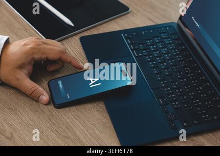 Hand using smartphone with AI interface beside laptop and tablet on office desk, suitable for password security, privacy protection, artificial intell Stock Photo