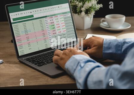 Hands typing on laptop with spreadsheet data and financial graphs on screen during online analysis and report management workflow in home office works Stock Photo