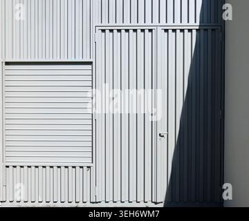 New prefabricated metal door and shutter on corrugated metal wall. Texture. Stock Photo