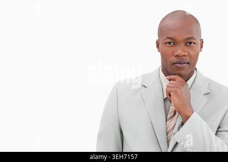 African American man posing, holding chin in studio wearing gray suit and striped tie, copy space Stock Photo