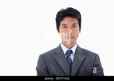 Mid Adult Japanese man posing in studio wearing charcoal gray suit, white shirt, dark navy tie Stock Photo