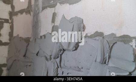 Close up view of wet grey plaster on concrete block wall. Shows textured cement application during construction or renovation. Raw, industrial backgro Stock Photo