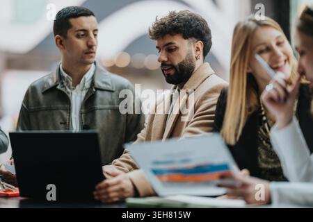 Young professionals collaborating on a laptop during an informal business meeting in a modern workspace Stock Photo