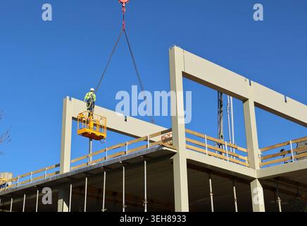 Unrecognizable worker on a scissor lift during the installation of new building pillars in the construction site Stock Photo
