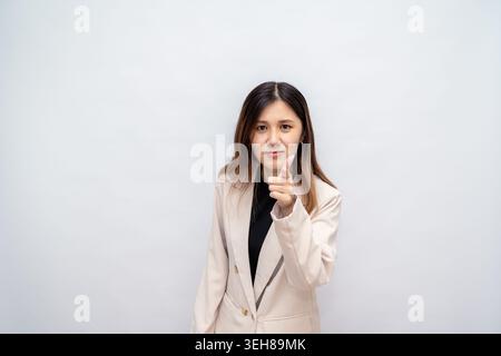 A young woman in formal attire confidently poses with a determined expression and a fist gesture, symbolizing motivation, success, and positive energy Stock Photo