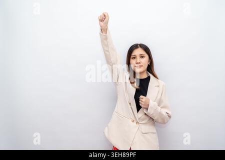 A young woman in formal attire confidently poses with a determined expression and a fist gesture, symbolizing motivation, success, and positive energy Stock Photo