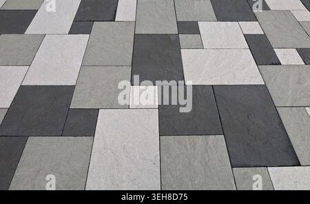 Black, white and gray concrete tiles of different shapes in an outdoor pavement. Background and texture. Stock Photo