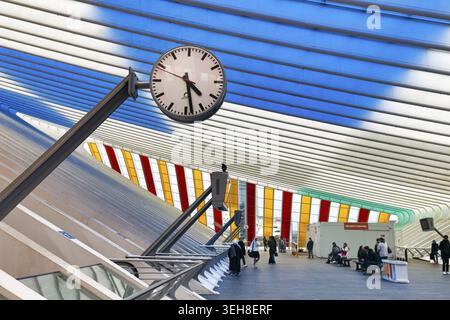 Distinctive station clock, timeless dial, colorful art installation by Daniel Buren, roof construction in station concourse, Gare de Liege-Guillemins Stock Photo
