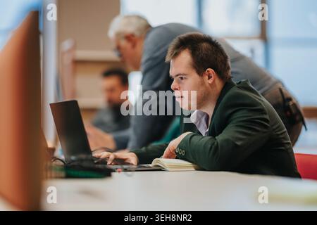 Young man with Down syndrome working on laptop during a business training session with mentor Stock Photo