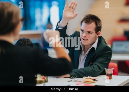Young man with Down syndrome raising his hand in a business meeting with colleagues Stock Photo