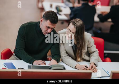 Two colleagues collaborating on a business project at a modern office desk, reviewing notes together Stock Photo
