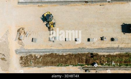 Aerial view of a yellow forklift moving materials at a construction site with stacks of bricks on gravel ground Pancevo, Vojvodina, Serbia. Stock Photo