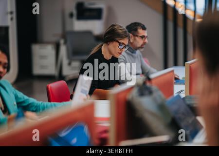 Focused coworkers working at open office desks in a modern business workspace Stock Photo